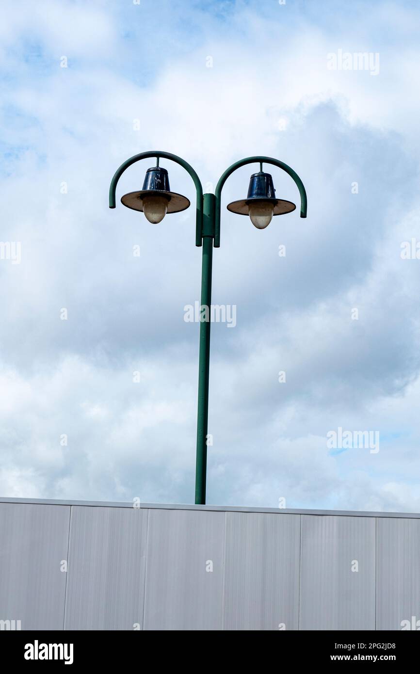 Double street light behind white building site fence in Crewe Cheshire UK Stock Photo