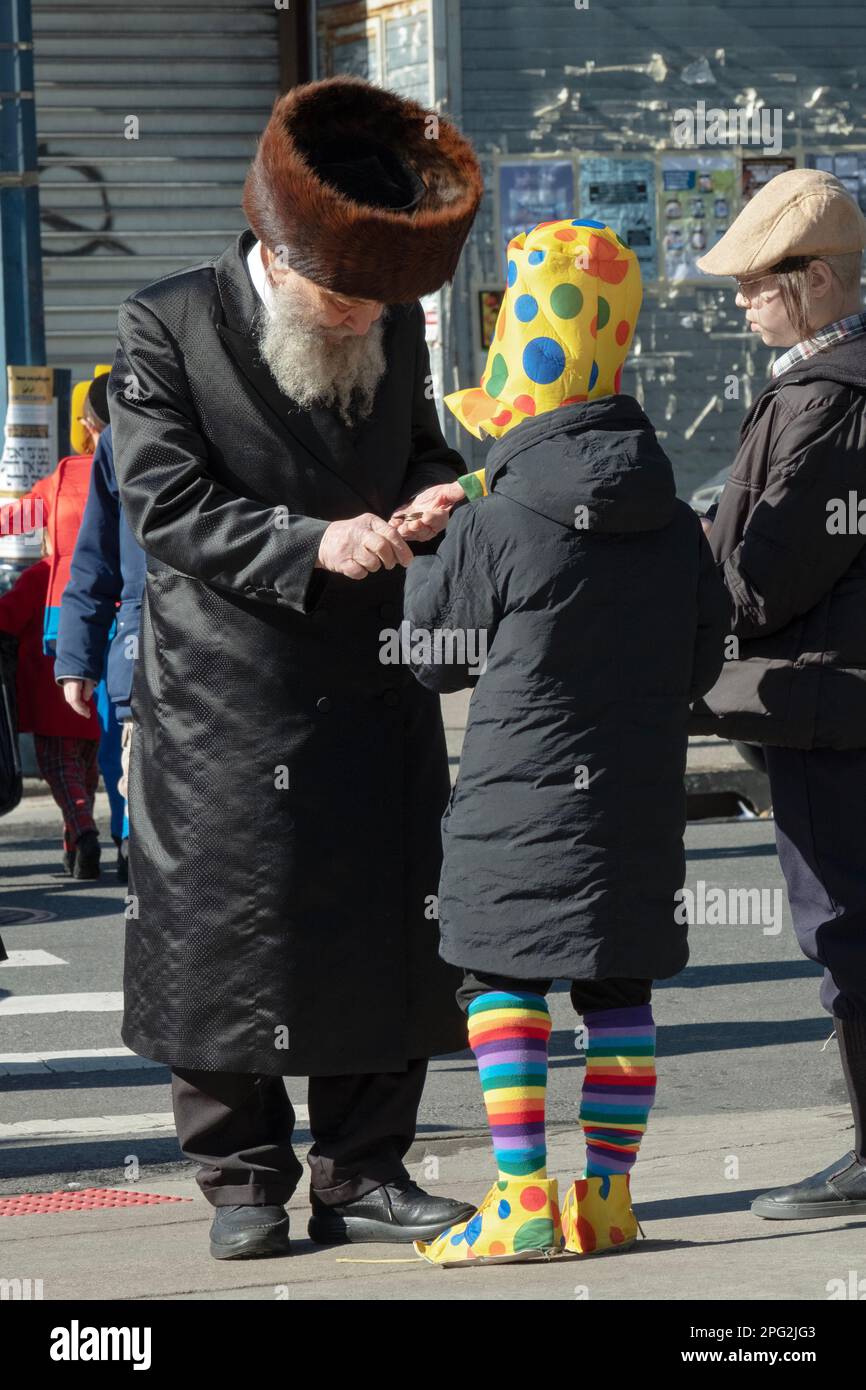 An older Hasidic Jewish man fulfills his Purim obligation of giving charity. In Brooklyn, New York. Stock Photo