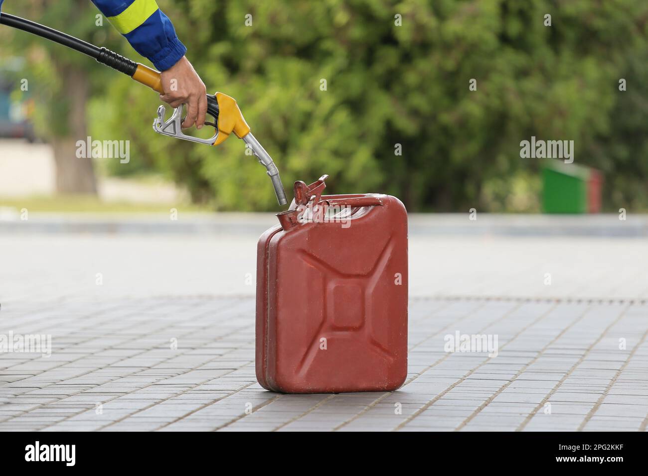 A man fills jerry cans at a gas station. A man fills gasoline in a