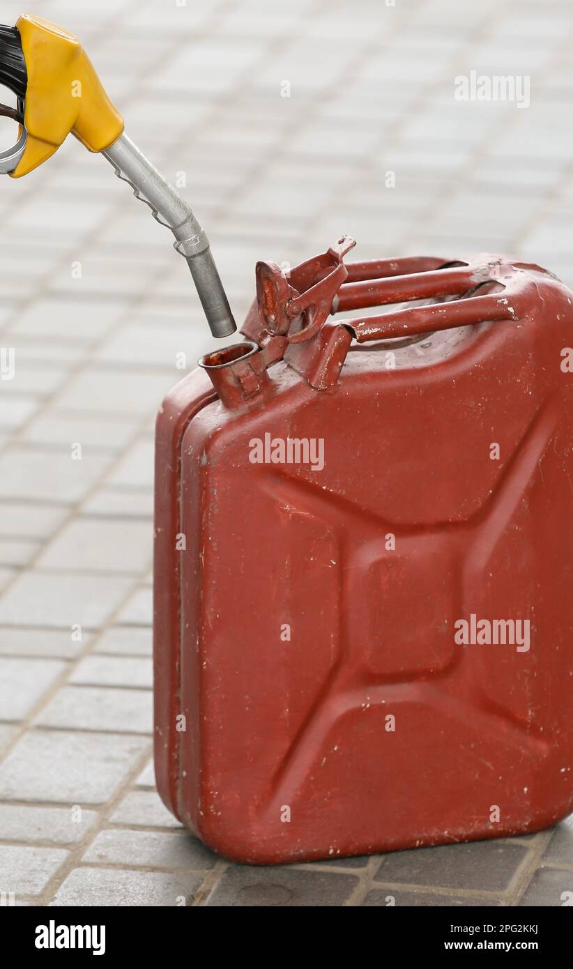 A man fills jerry cans at a gas station. A man fills gasoline in a