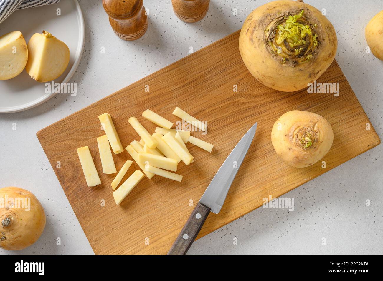 Cutting fresh yellow turnip for cooking healthy vegan food on white background. View from above