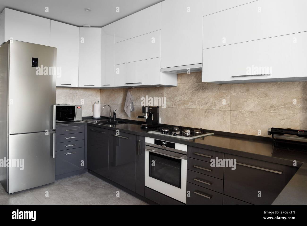 The kitchen in the apartment. The design of the kitchen room. Gray kitchen interior with white cabinets. Built-in oven in the interior of the kitchen. Stock Photo