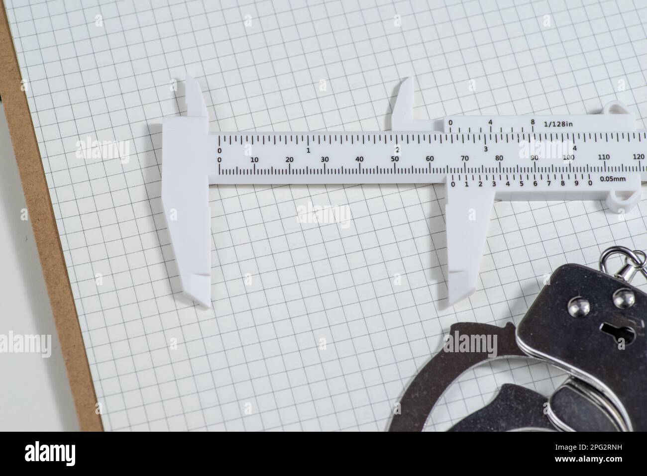 Slide calipers and handcuffs on a graph paper,copy space Stock Photo