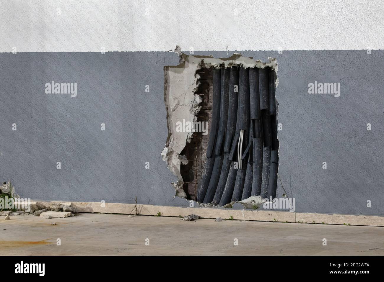 Old electrical wires in damaged plastic insulation, in mounting hole in the wall. Dangerous and