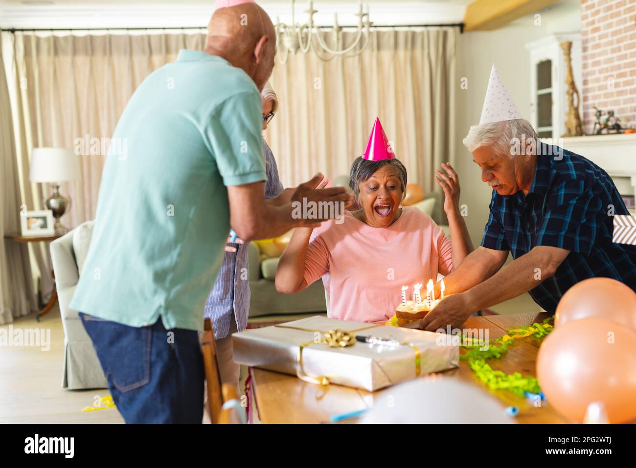 Happy group of diverse senior friends celebrating birthday with cake and presents Stock Photo