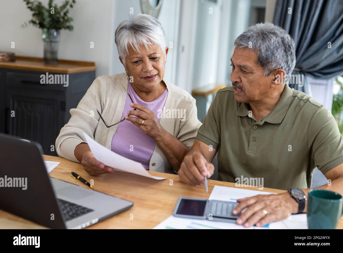 Biracial senior couple with calculator and bills analyzing finances and  expenses on table at home Stock Photo - Alamy