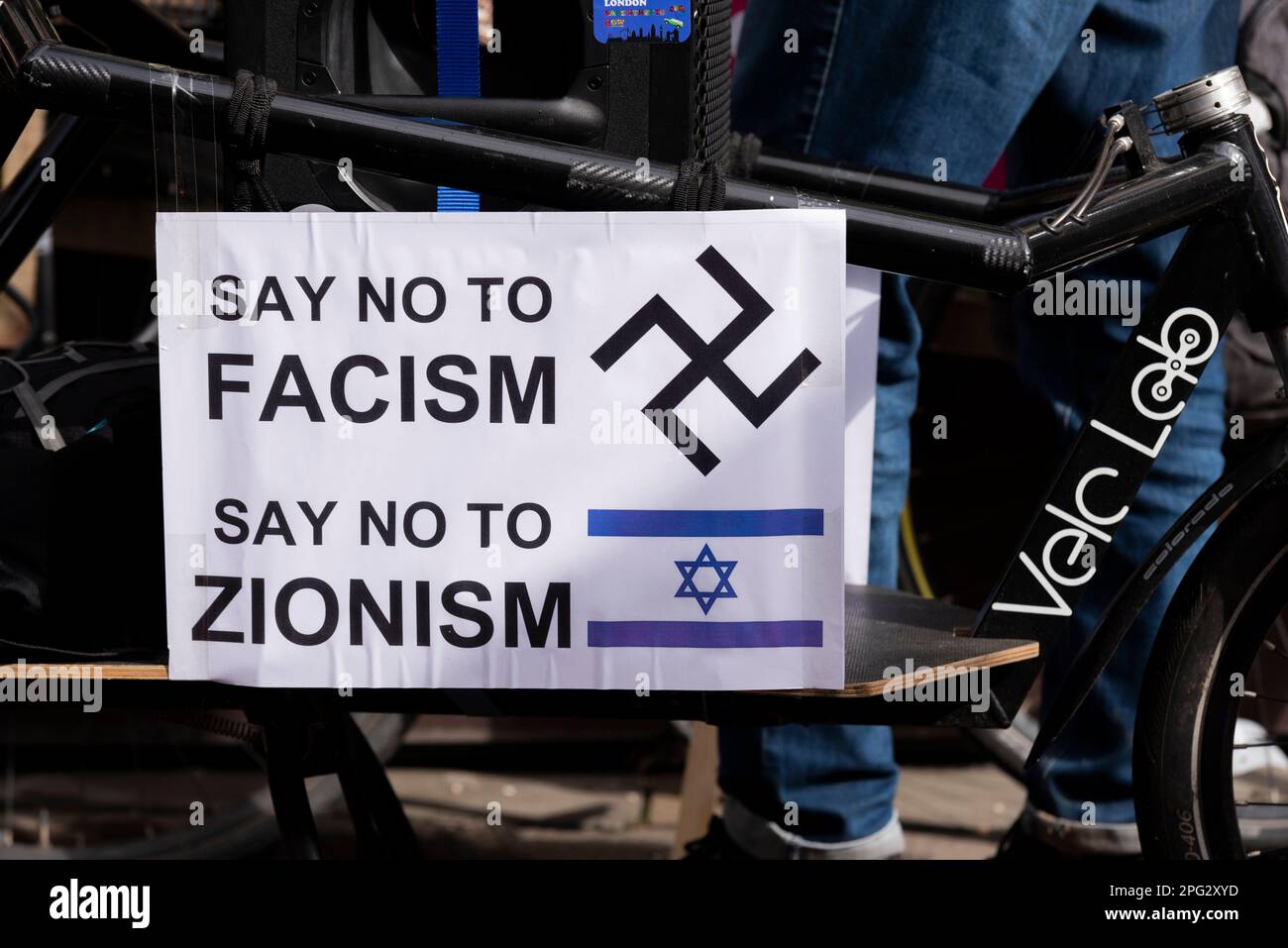Protest taking place in London on UN Anti Racism Day. Stand up to Racism. Bicycle with say no to Fascism, say no to Zionism banner, with Israel flag Stock Photo