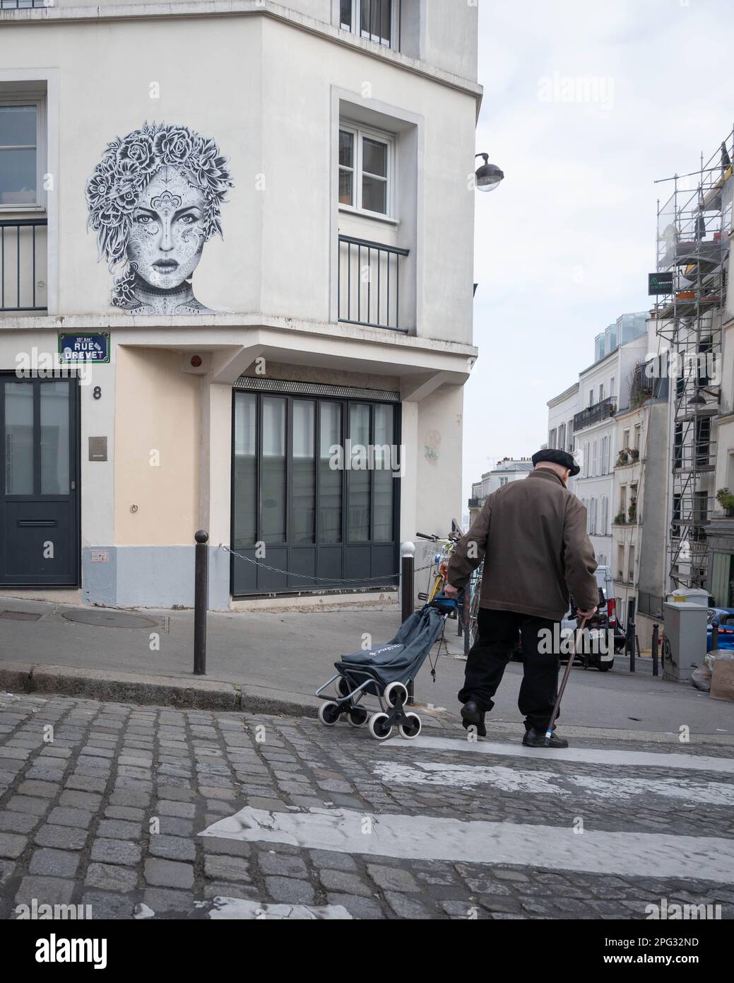 Old man with beret and shopping trolley waling past graffiti in Montmartre, Paris Stock Photo