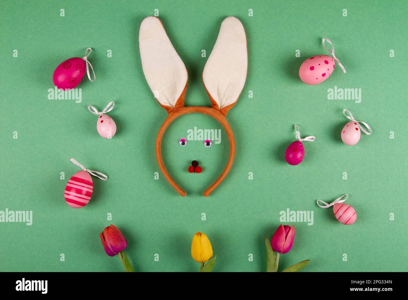 Amusing Easter backdrop in green hues featuring pink eggs and a bunny countenance Stock Photo