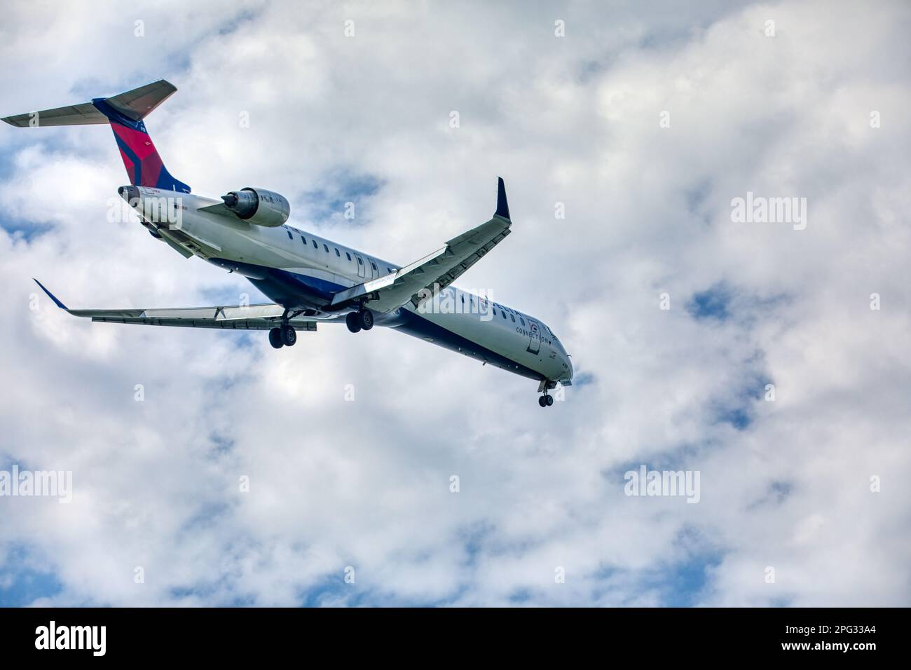 A Delta Connection Bombardier CRJ-900 twin-engine passenger jet approaches and lands at LaGuardia Airport runway 22 in East Elmhurst, Queens. Stock Photo