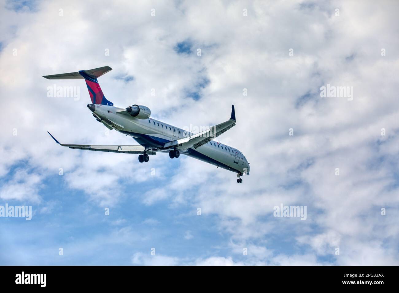 A Delta Connection Bombardier CRJ-900 twin-engine passenger jet approaches and lands at LaGuardia Airport runway 22 in East Elmhurst, Queens. Stock Photo