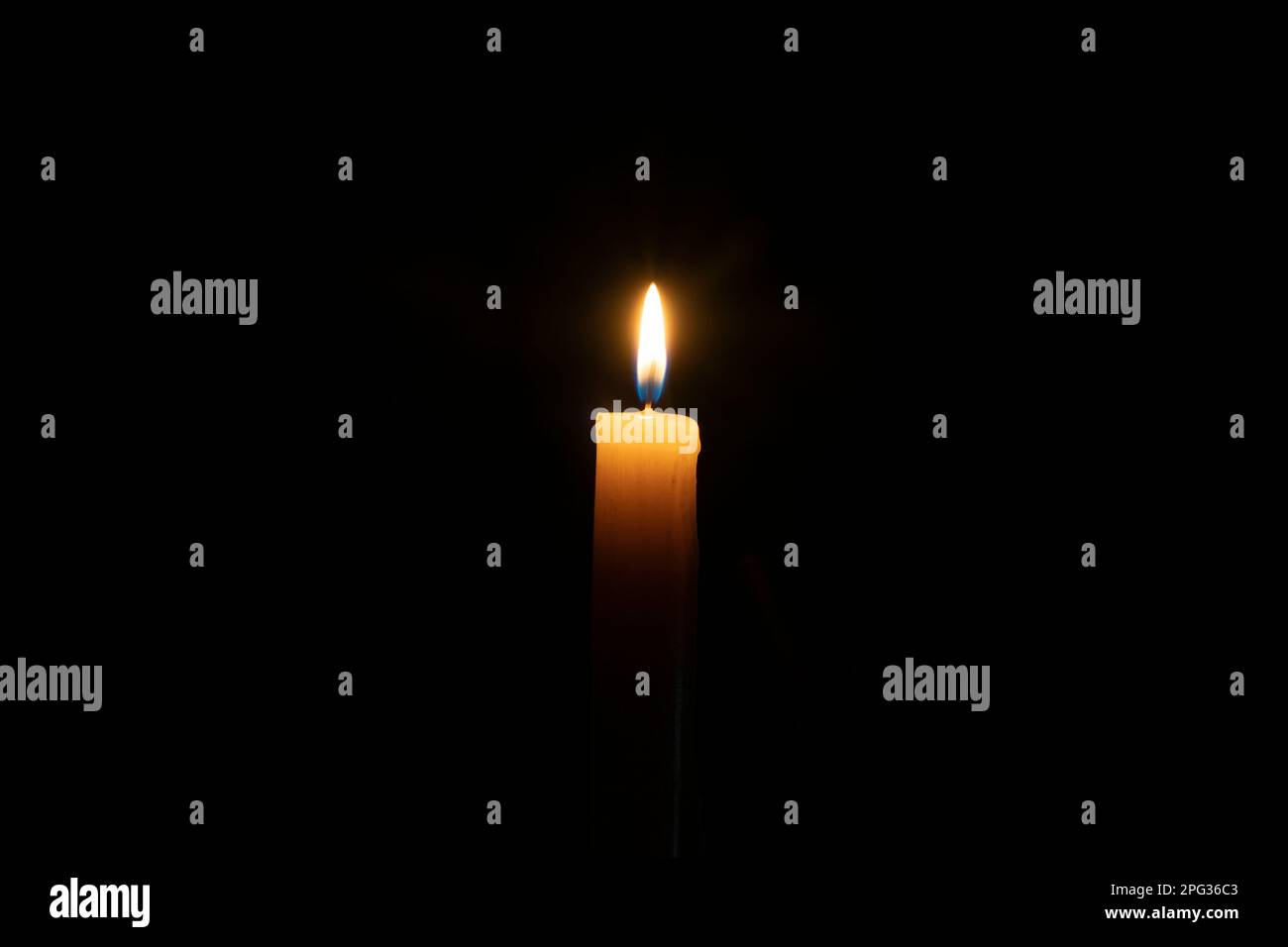 Isolated yellow candle burning on black background. The concept of