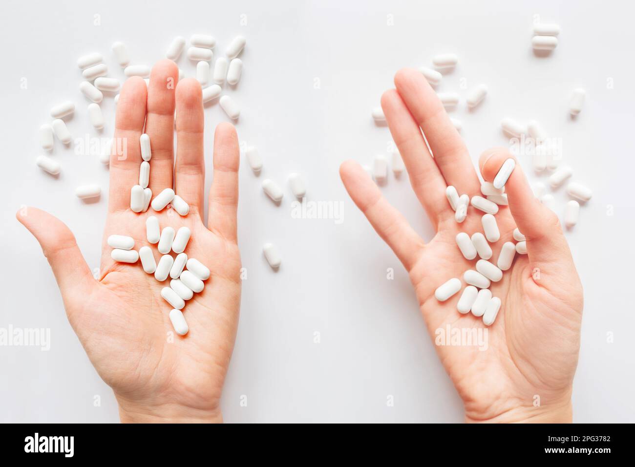 Palm hands full of white scattering pills. Capsules with medicines on light background. Flat lay, top view. Stock Photo