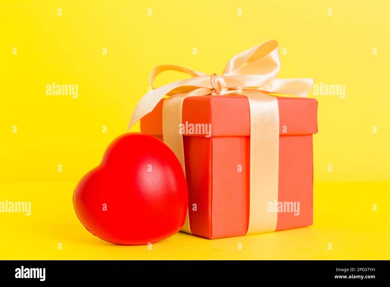 gift box with red bow and red heart on colored background. Perspective ...