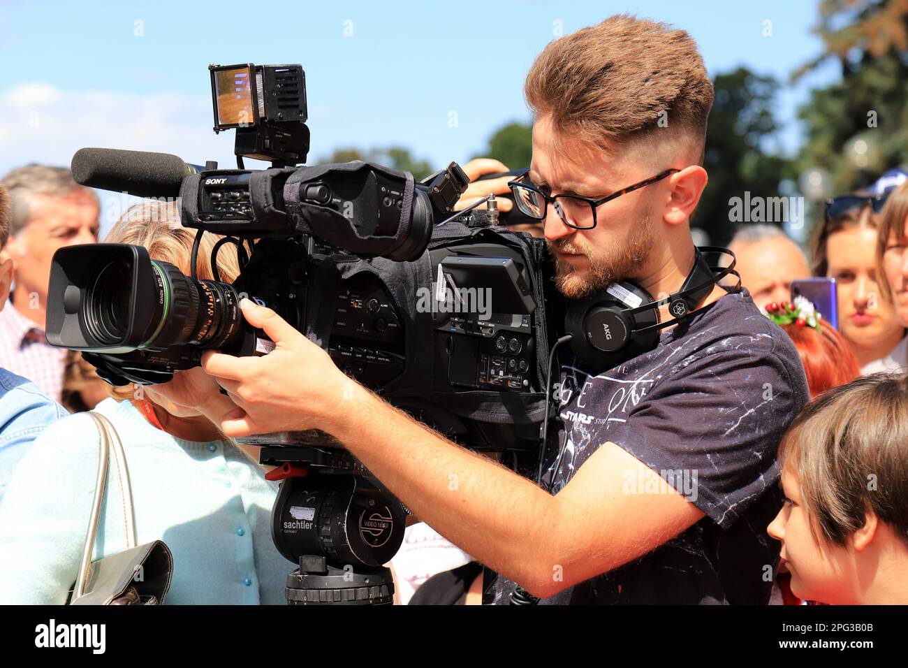 Operator with professional television camera shoots video at rally, protest, event. Journalist correspondent takes interview, live broadcast for TV ch Stock Photo