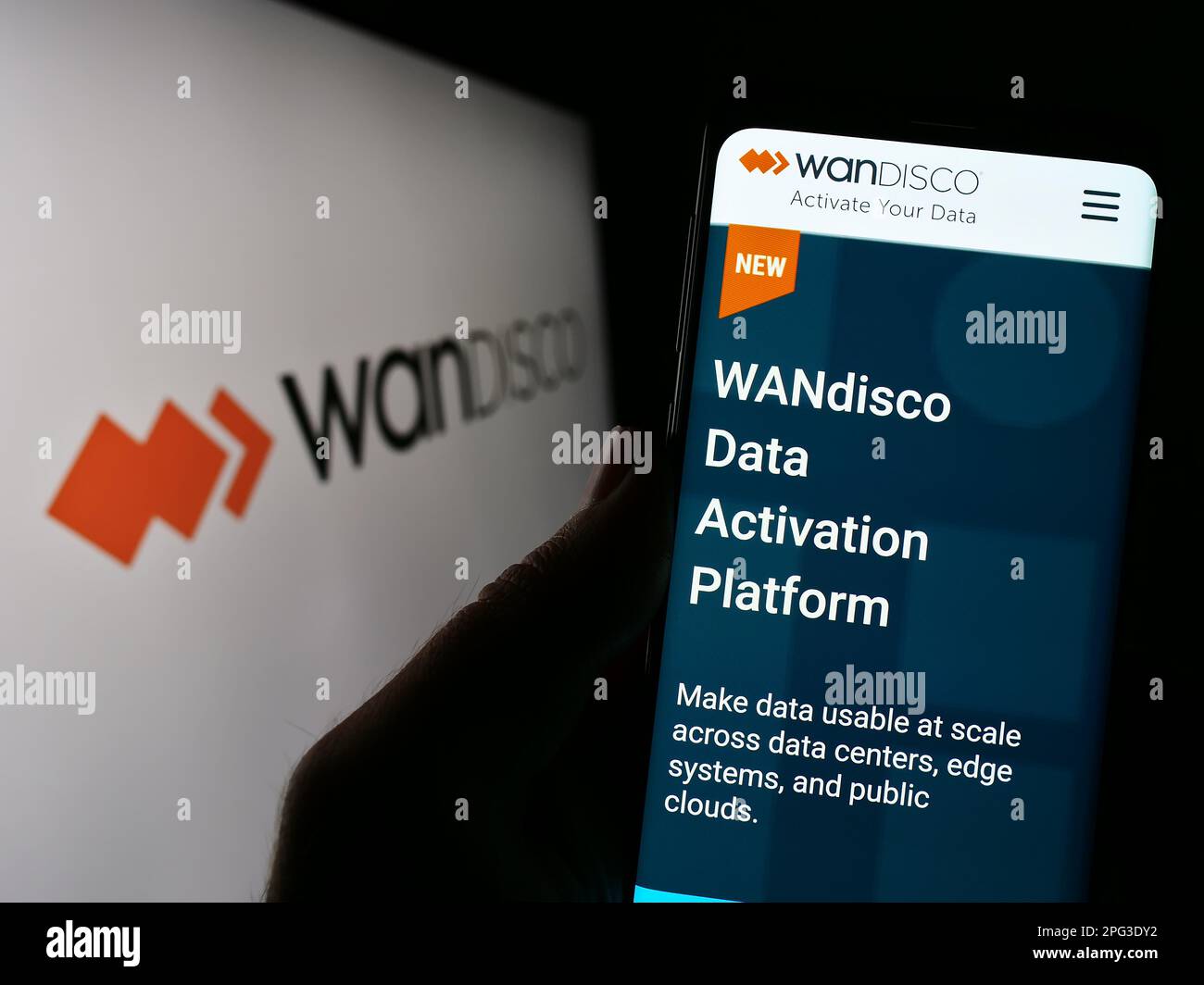 Person holding smartphone with webpage of software company WANdisco plc on screen in front of business logo. Focus on center of phone display. Stock Photo