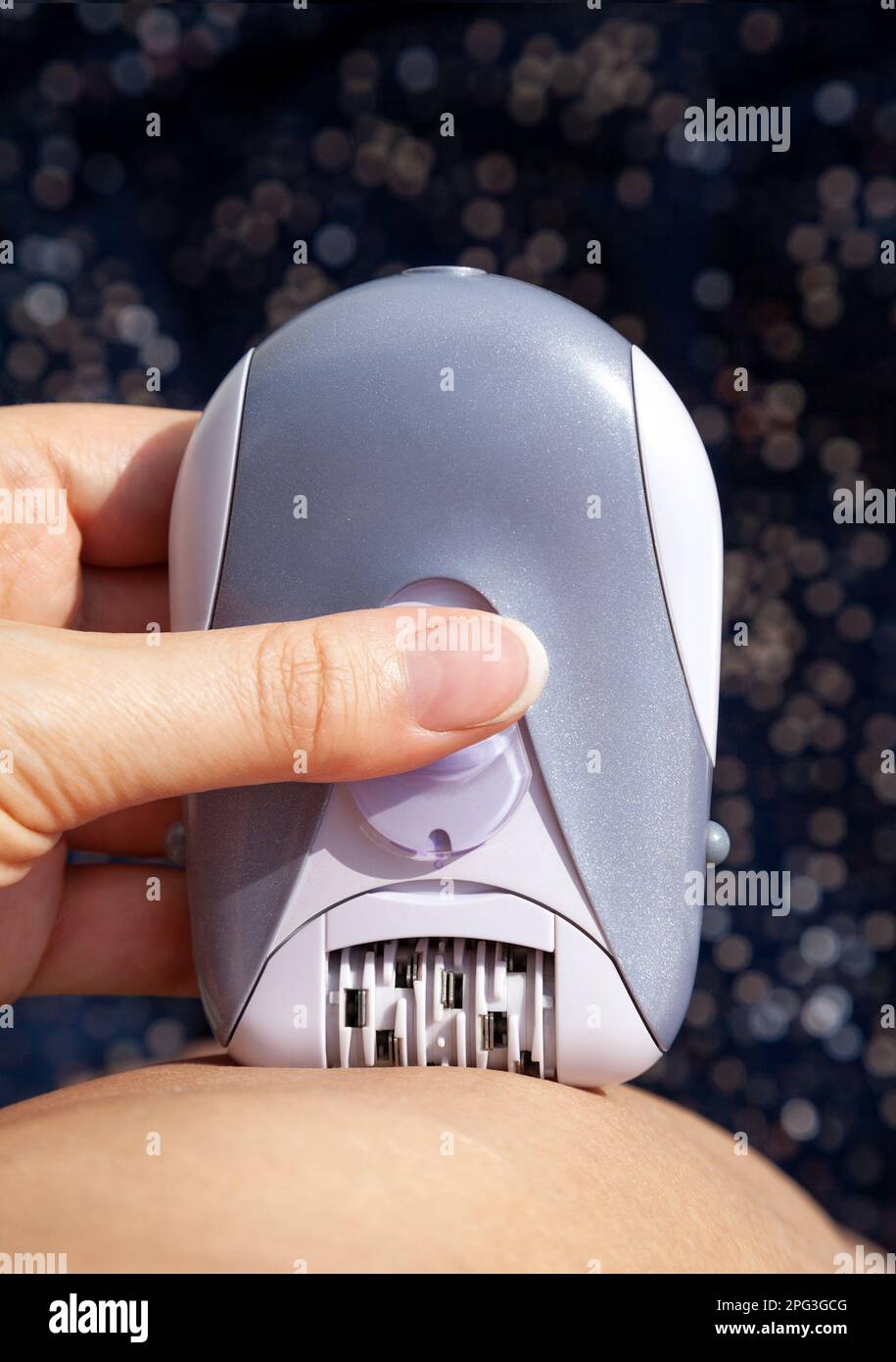 Woman using personal electrical epilator on herself at home. Hair
