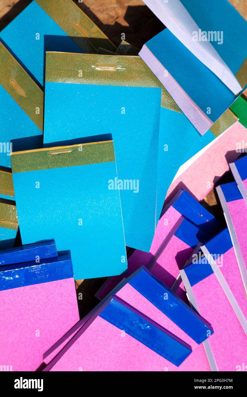 Many cheap small notepads in a messy heap, top view. A pile of blue and