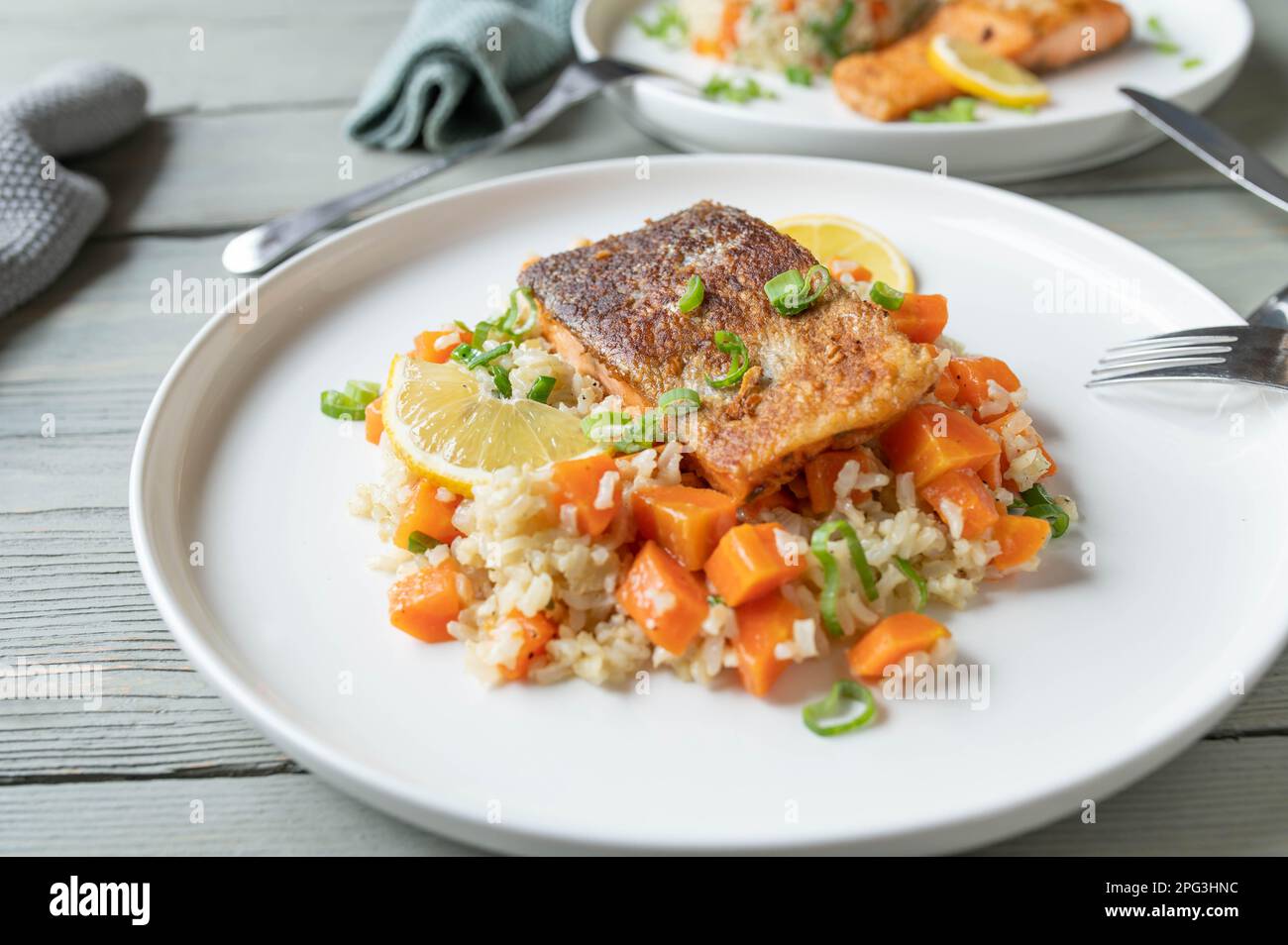 Fried salmon with skin served with brown rice and vegetables on a plate Stock Photo