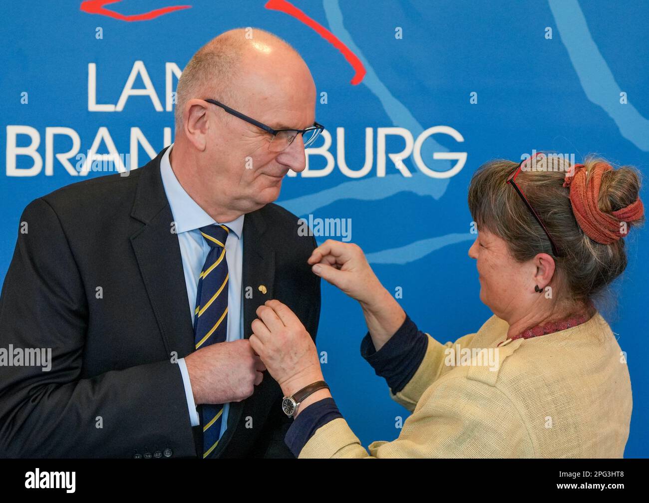20 March 2023, Brandenburg, Potsdam: Brandenburg's Minister President Dietmar Woidke (SPD) receives the 'Golden Pretzel of Honor' from Cottbus master baker Diana Lewandowski. The 'Golden Pretzel' is the seal of quality of the bakery and confectionery trade. Woidke received the award for his political services to the craft sector in Brandenburg. Photo: Soeren Stache/dpa Stock Photo