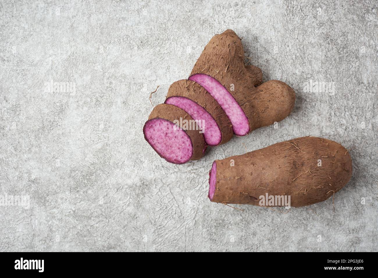 sliced purple yam on a white textured surface, dioscorea alata, aka ube, violet yam, water or greater yam, purple-fleshed tubers used in cuisine Stock Photo