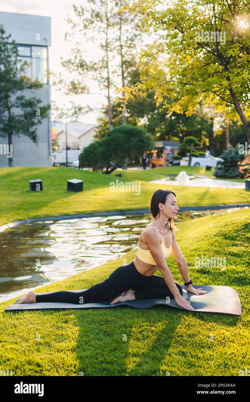 Full length portrait of a athletic woman doing pilates on a mat outside