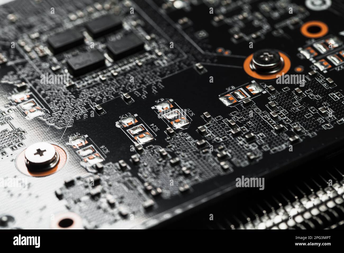 Black printed circuit board with microchips and capacitors, macro photo
