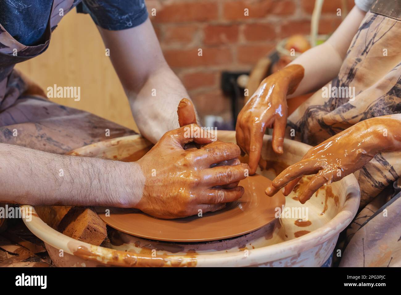 potter teaches the child. A craftsman sits on a bench with a potter's