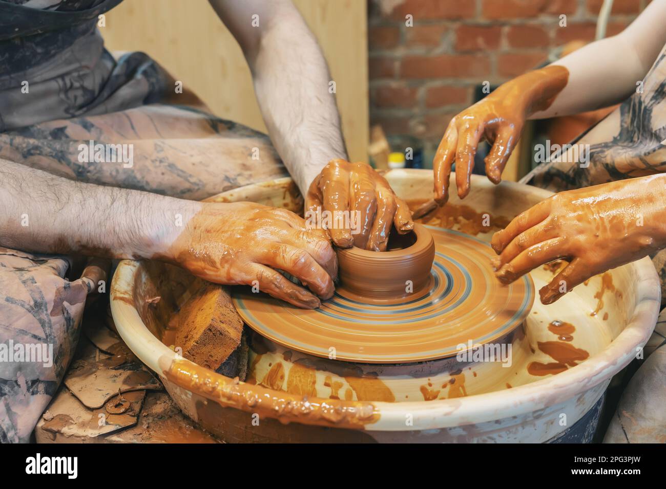potter teaches the child. A craftsman sits on a bench with a potter's