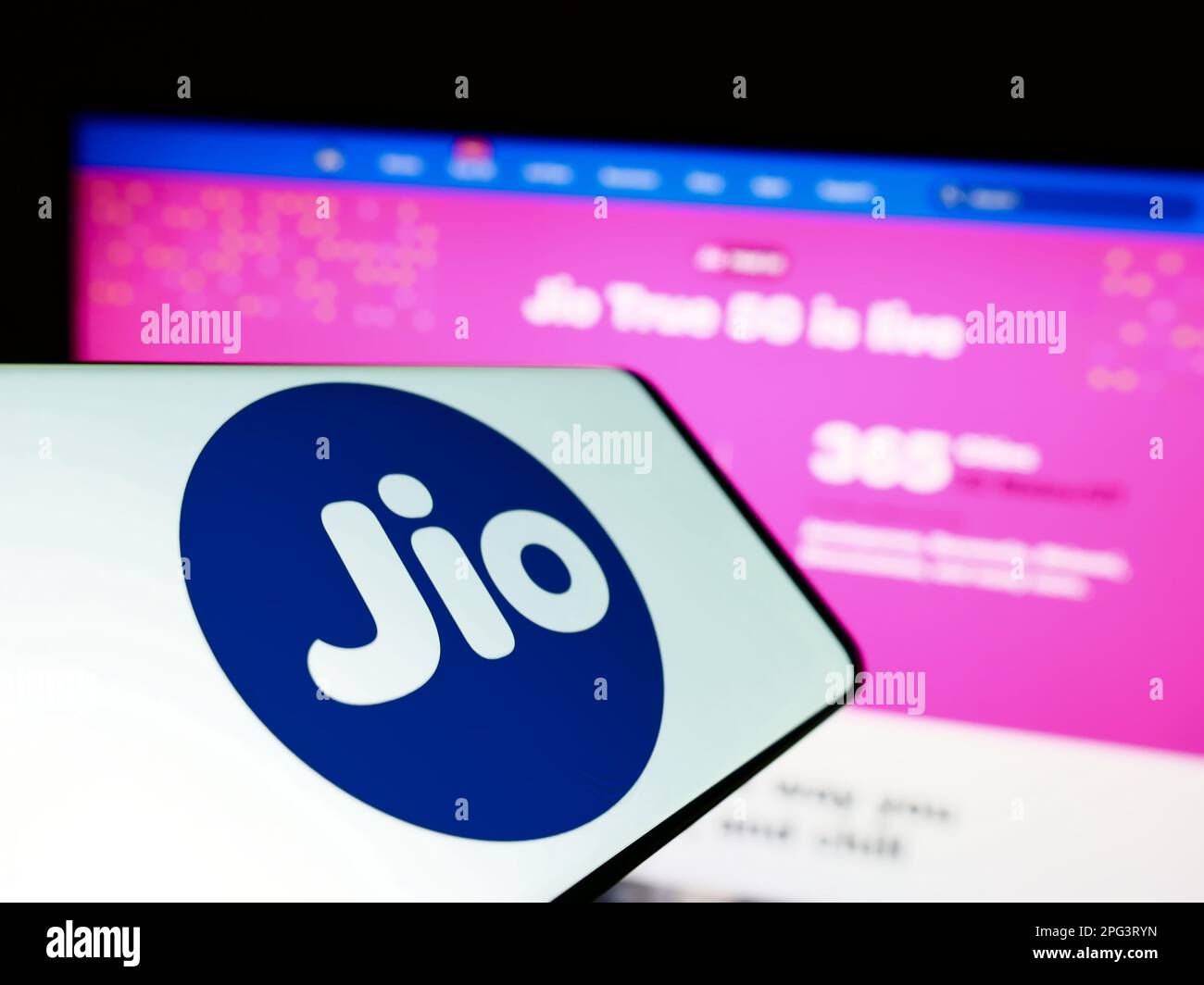 Mobile phone with logo of Indian telecommunications company Reliance Jio on screen in front of website. Focus on center-left of phone display. Stock Photo