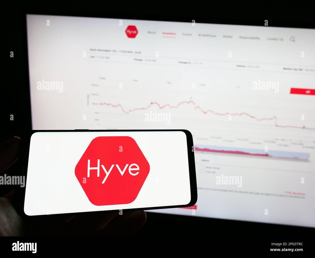 Person holding mobile phone with logo of British event management company Hyve Group plc on screen in front of web page. Focus on phone display. Stock Photo