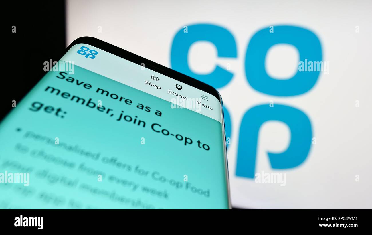 Mobile phone with webpage of retail company Cooperative Group Limited on screen in front of