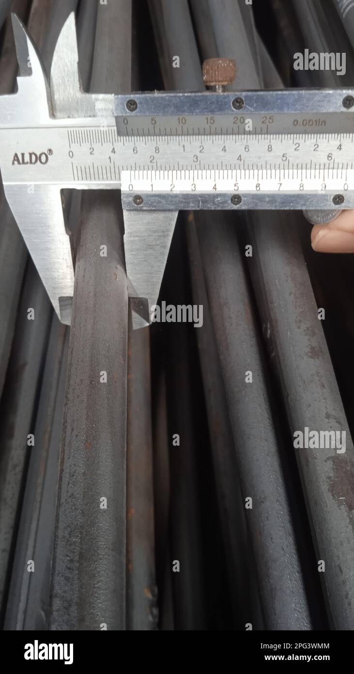 The worker measures the diameter of the iron bar with a vernier caliper ...
