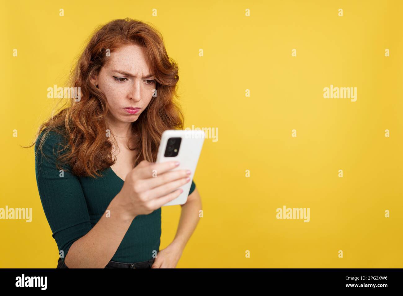 Worried redheaded woman using a mobile phone Stock Photo
