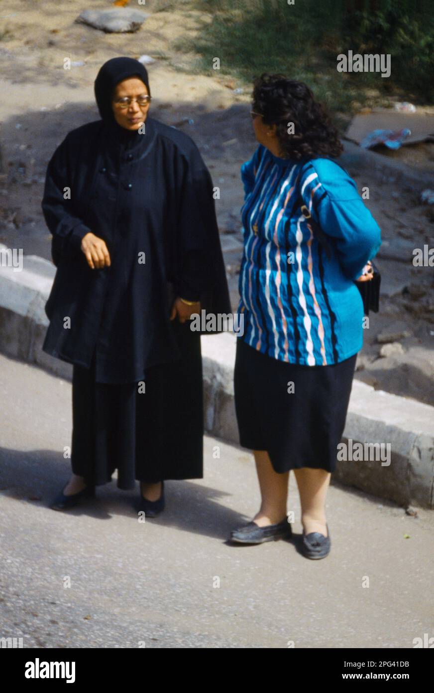Luxor Egypt Two Women Having a Conversation in the Street - Western and Traditional Dress Stock Photo