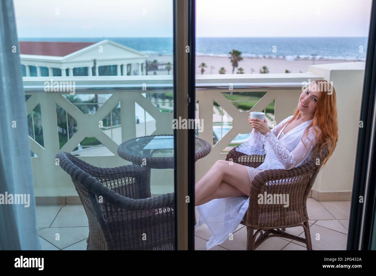 Woman sitting on a terrace and holding a cup Stock Photo - Alamy
