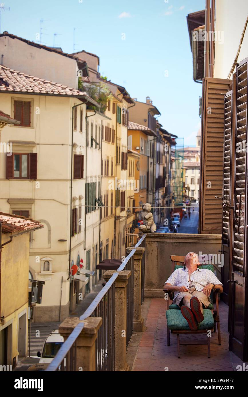 Man lying down relaxing on urban balcony, Florence, Italy Stock Photo