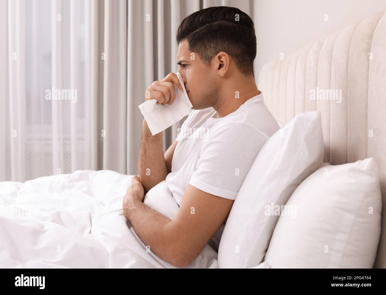 Sick man with tissue suffering from cold in bed at home Stock Photo Alamy