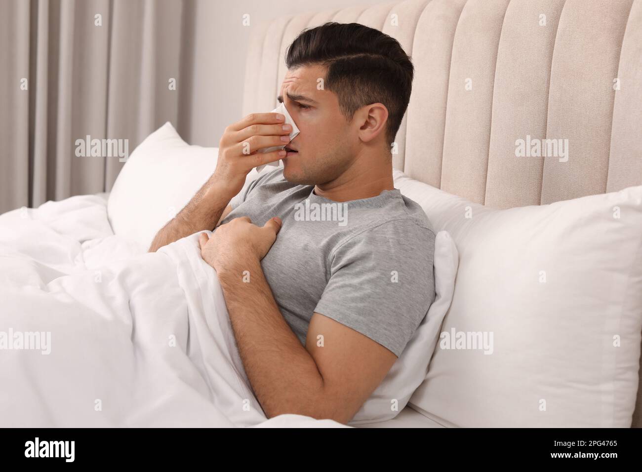 Sick man with tissue suffering from cold in bed at home Stock Photo Alamy