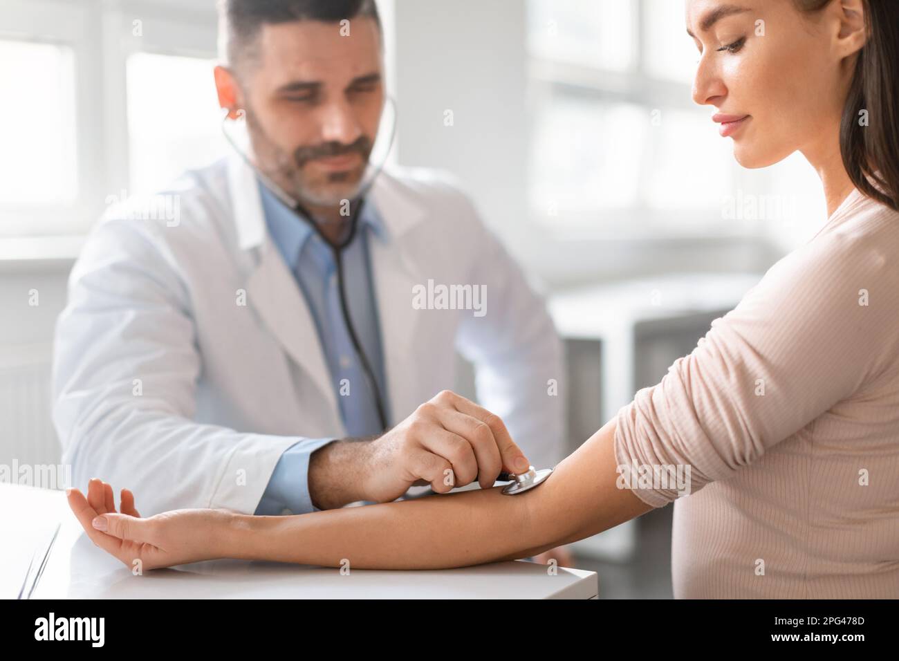 Male physician manually taking blood pressure using sphygmomanometer