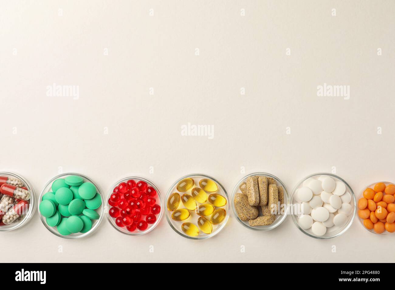 Different dietary supplements in bowls on white background, flat lay