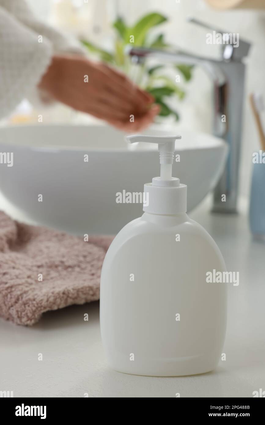 Woman washing hands with liquid soap in bathroom, focus on dispenser. Space for text Stock Photo