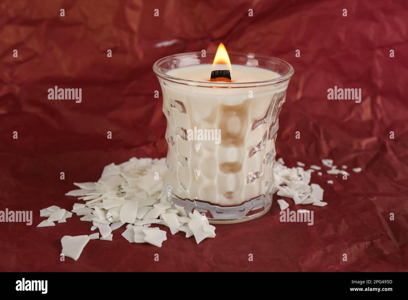 Burning soy candle and wax flakes on crumpled red paper Stock Photo Alamy