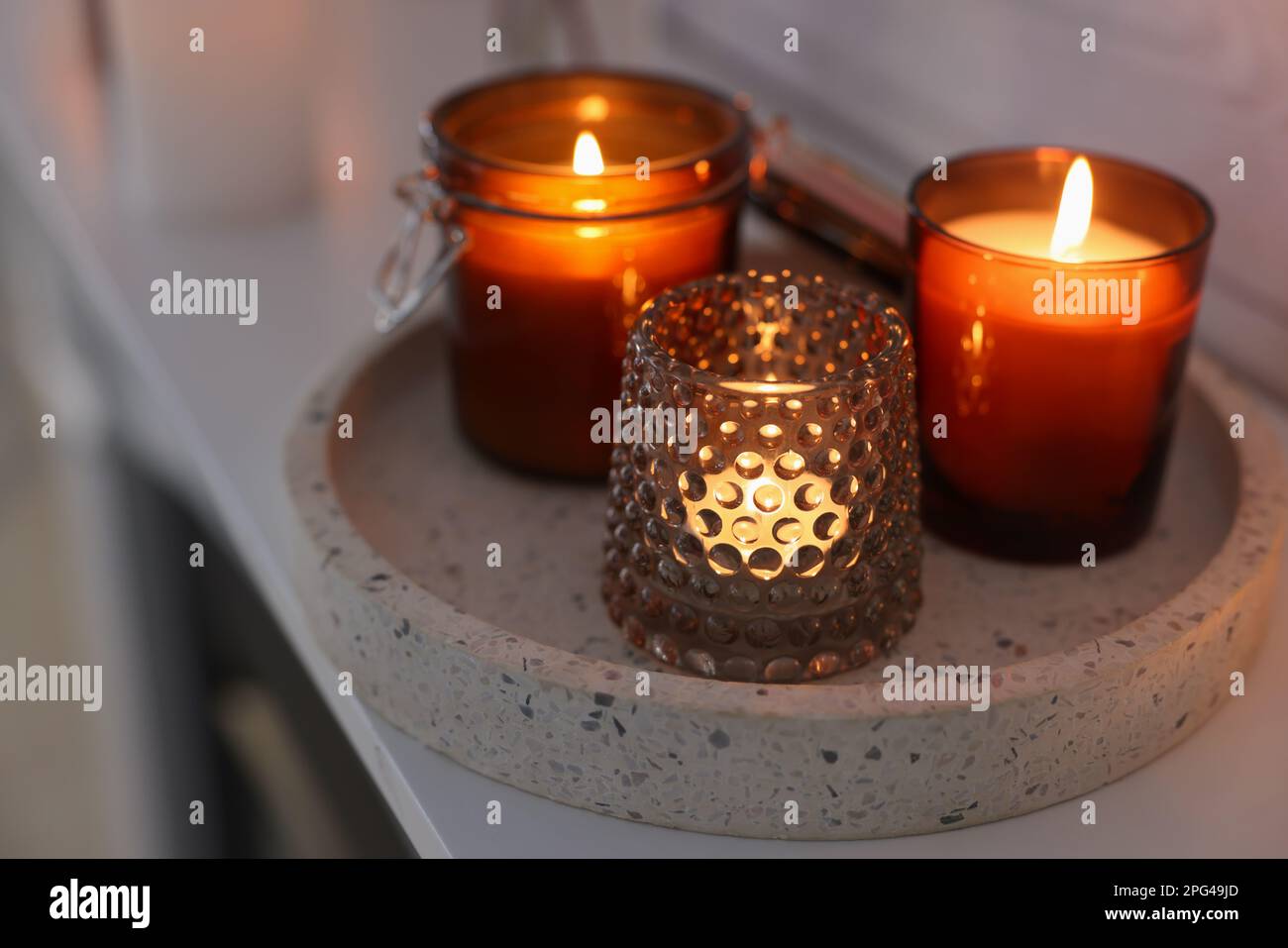 Burning candles on mantel near white wall indoors Stock Photo Alamy