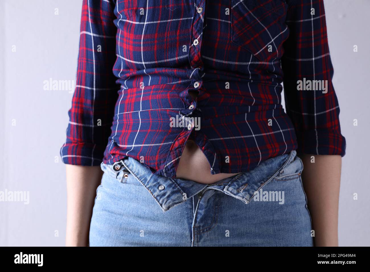 Woman wearing tight jeans and shirt on light grey background, closeup