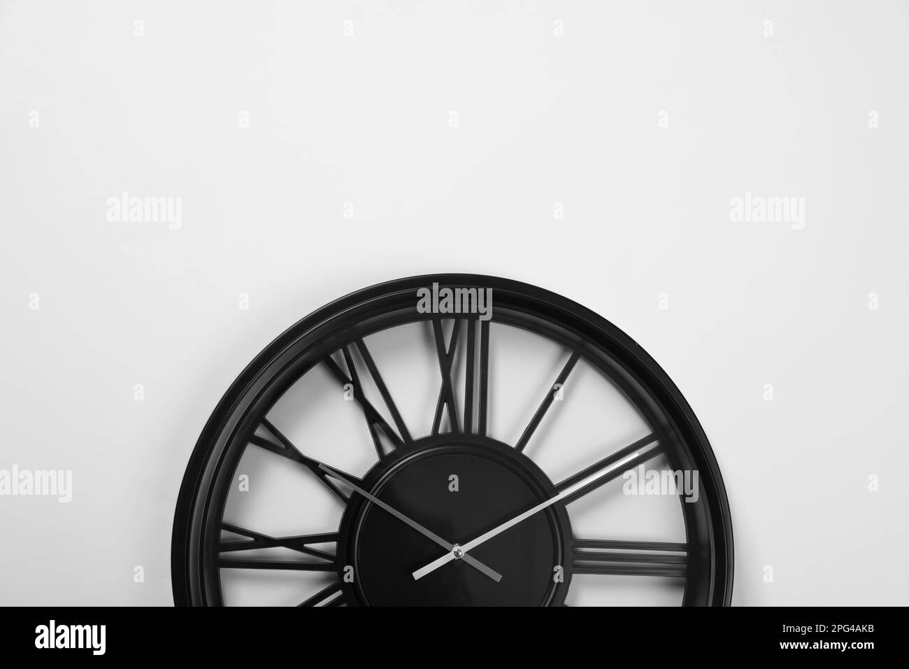 Stylish analog clock hanging on white wall, space for text Stock Photo