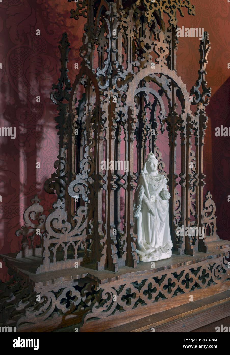 A small marble statue of Queen Victoria stands in a intricate carved