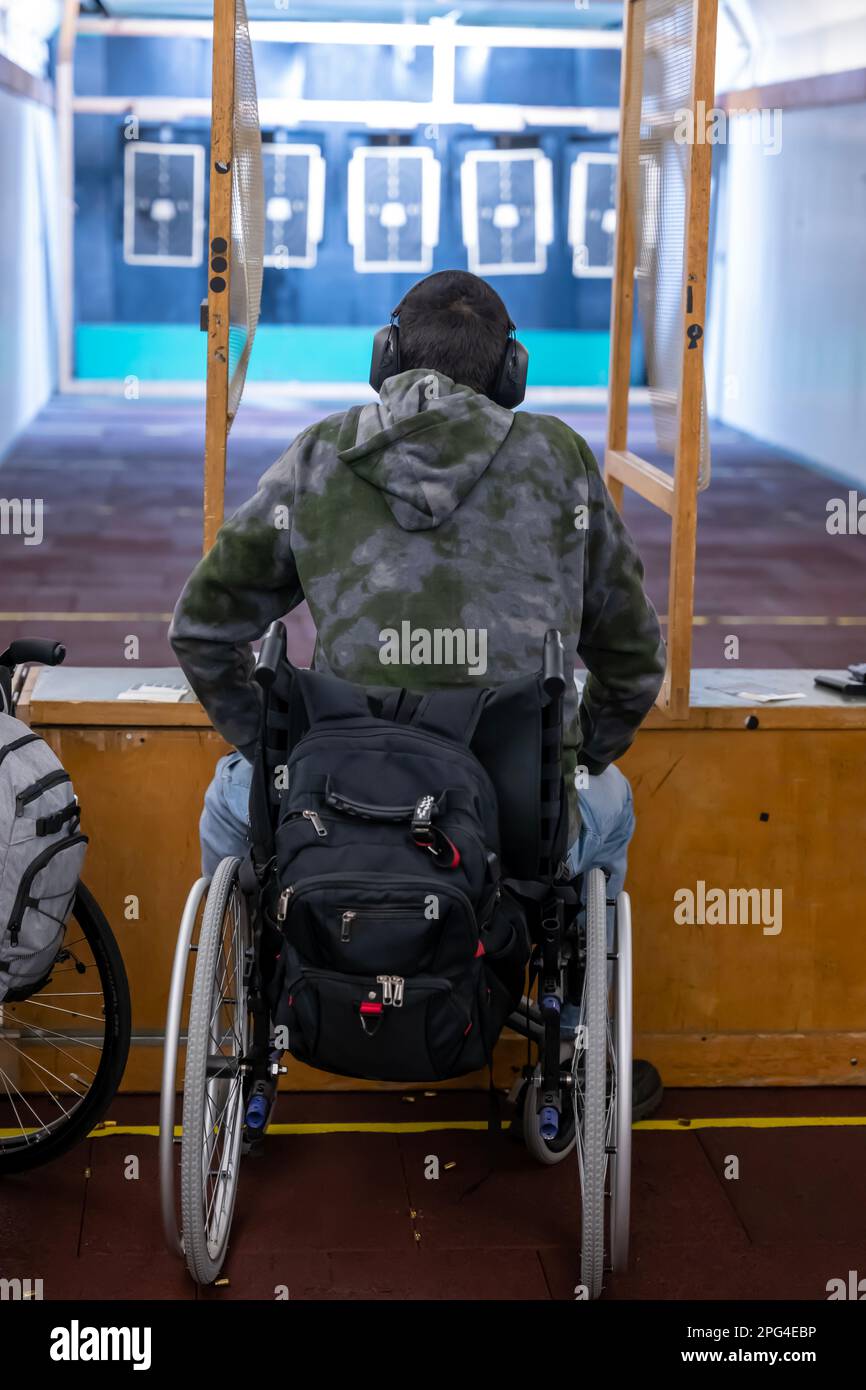 Man in Wheelchair Shooting with a Gun on Shooting Range with Target in