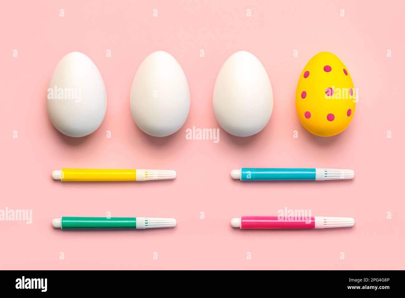 Happy Easter. Colorful easter painted egg and three white easter eggs with colored markers over pink background Stock Photo