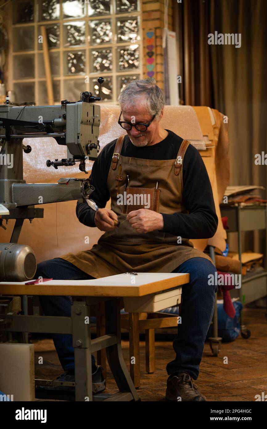 vertical photo of craftsman sitting adding sewing thread in a sewing
